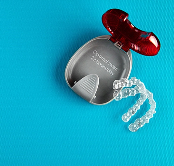 A set of Invisalign aligners sitting next to a protective case