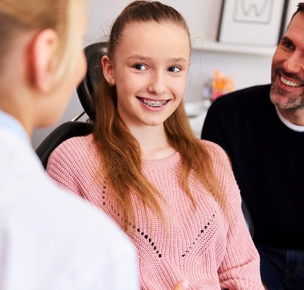 Young lady with braces and her father listening to Frisco orthodontist
