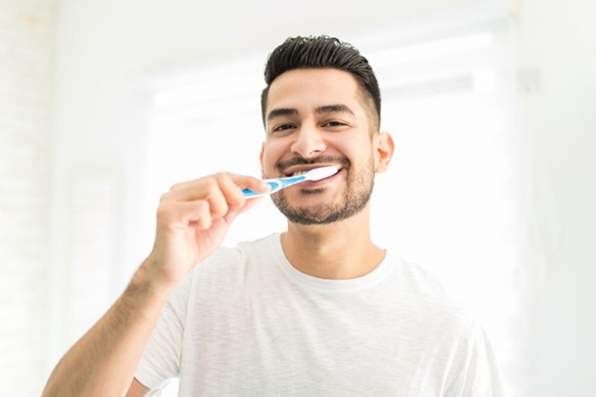man brushing teeth in bathroom 