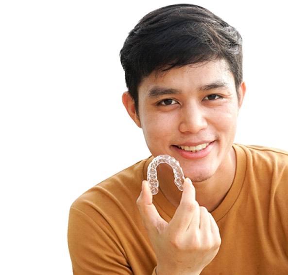 A young man holding an Invisalign aligner