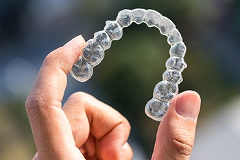 Patient holding Invisalign clear aligner outside